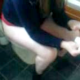 A lower-quality video featuring a woman taking a soft shit while sitting on a toilet and peeing. Camera then zooms out to show her wiping her ass repeatedly